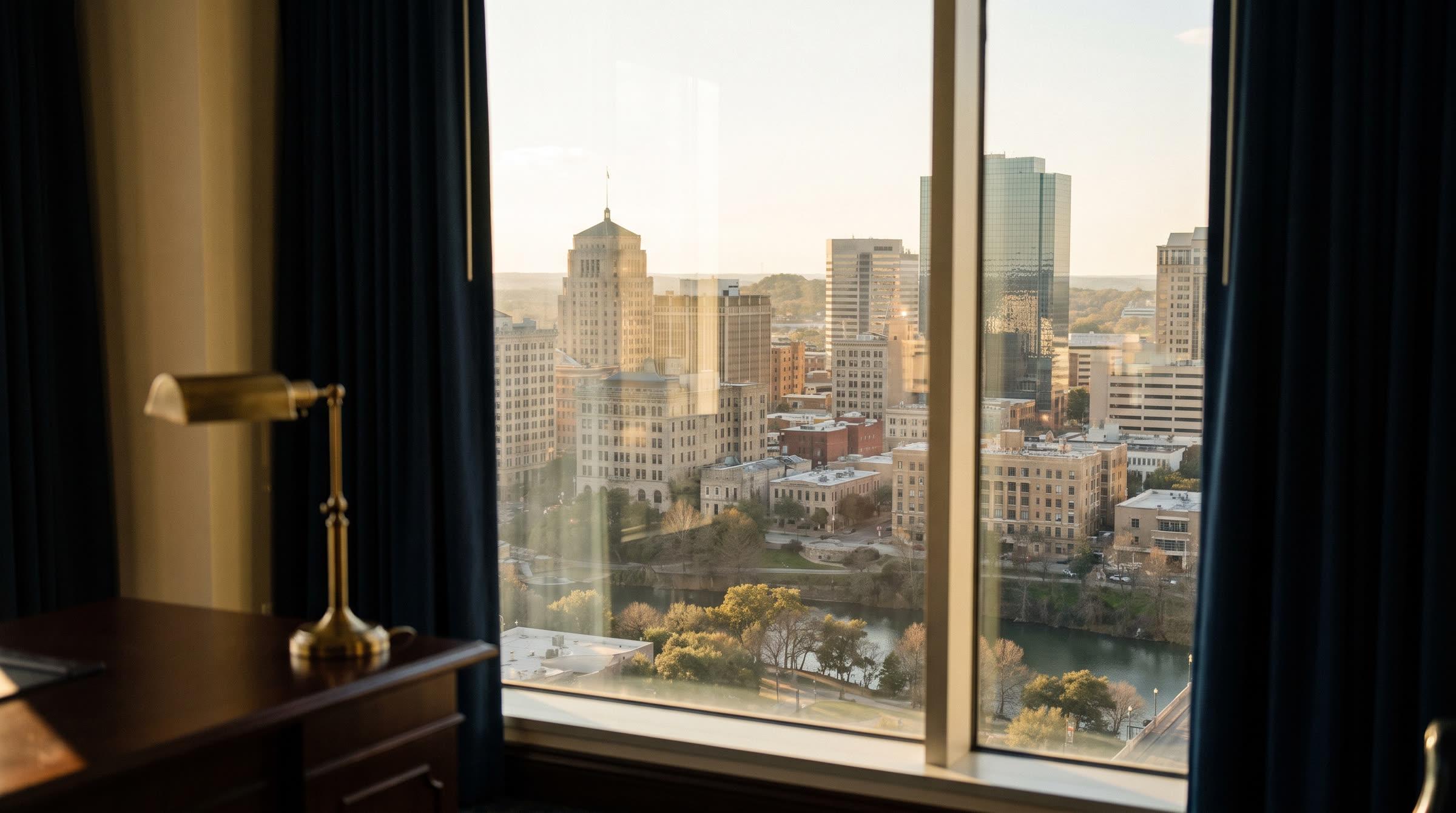 A downtown skyline and a tree-lined river seen from an office window