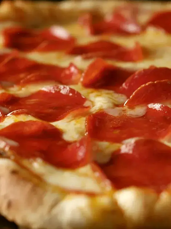A whole pepperoni pizza with a golden crust, from the pizzeria concept
