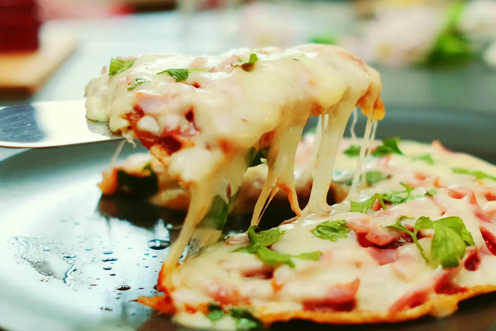 A slice lifted from a fresh pie, pulling long strands of melted mozzarella.